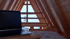 Een laptop op een houten tafel in een kamer met houten wanden en een schuine kap.