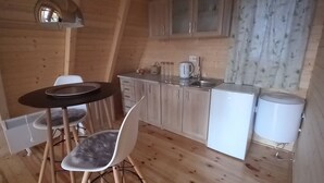 Een kleine keuken met houten kastjes, een eettafeltje en een witte stoel.