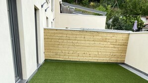 A rooftop with artificial grass, a wooden wall, and a window. - Maison duplex 90 m2 6 km from Bordeaux center (Floirac)