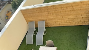A rooftop patio with a table and chairs, surrounded by artificial grass and a wooden wall. - Maison duplex 90 m2 6 km from Bordeaux center (Floirac)