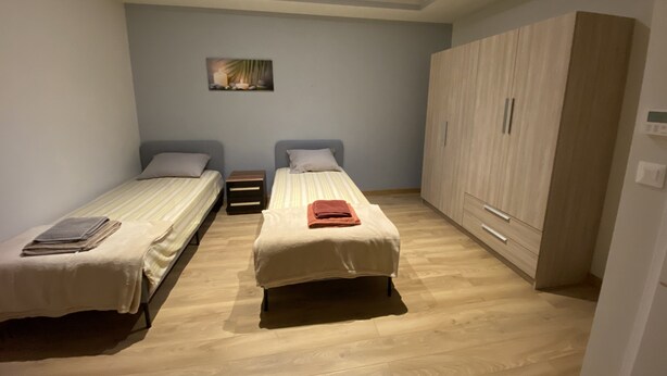 A room with two single beds, a wooden wardrobe, and a small table between the beds. - Maison duplex 90 m2 6 km from Bordeaux center (Floirac)