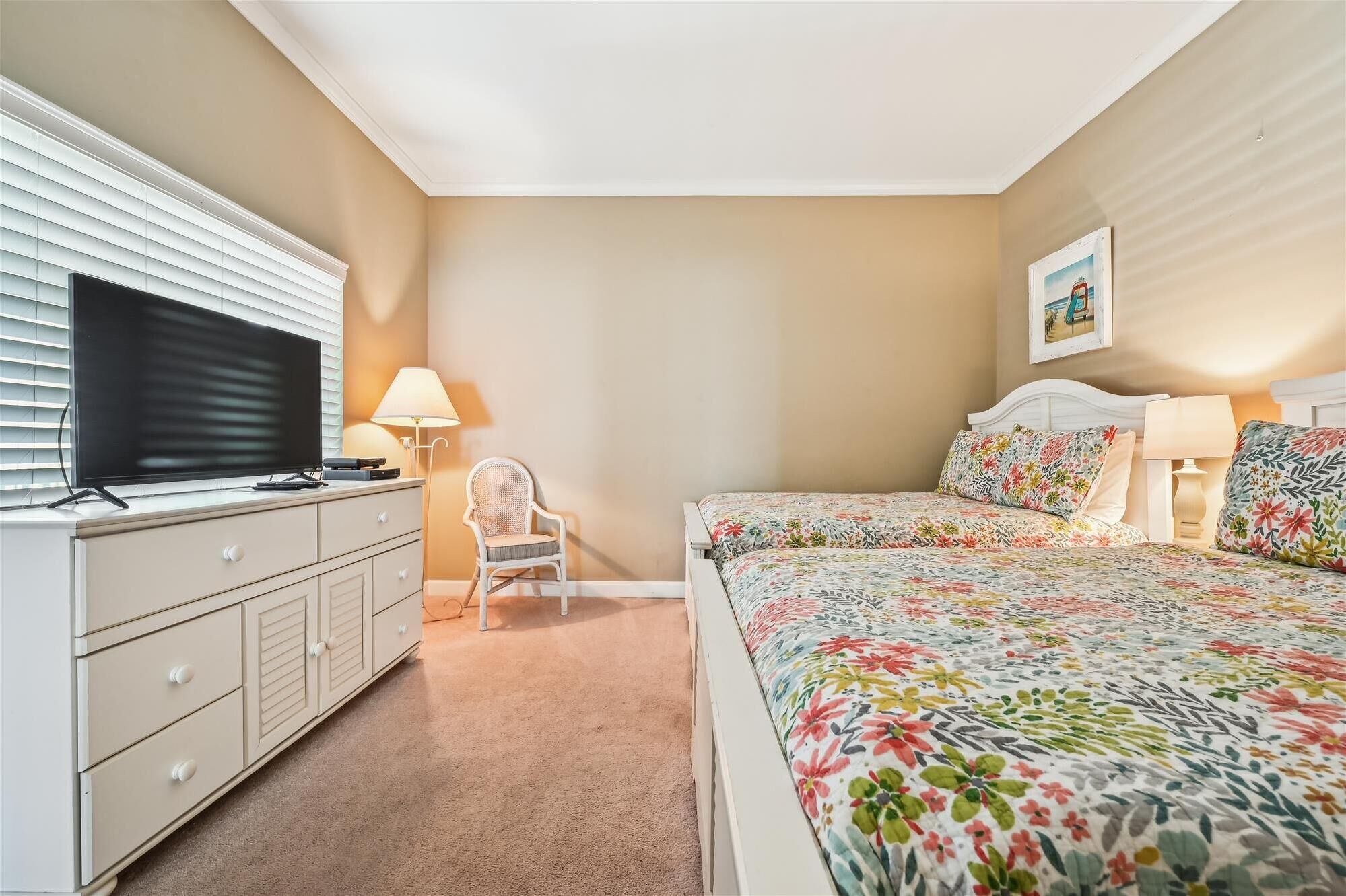 Une chambre à coucher avec un lit, un téléviseur posé sur une commode, une chaise et une lampe.