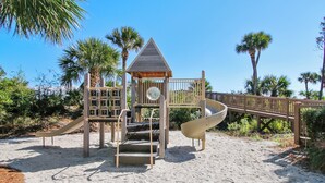 A playground with a slide, climbing area, and a small shelter.