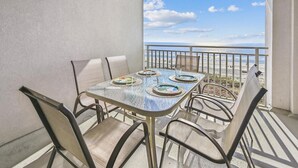 A balcony with a table and chairs, overlooking a beach. - 5th Floor Villa, Steps to the Beach & Downtown (Hilton Head Island)