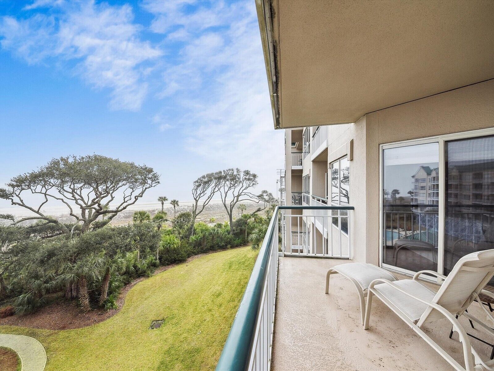 A balcony with a view of a landscaped area and distant trees.
