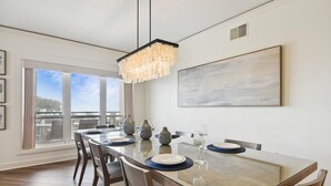 A dining area with a long table, chairs, and a chandelier.