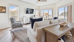 A spacious living room with a sofa, a coffee table, and a TV mounted on the wall.
