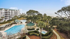 A resort with multiple swimming pools, a large building with balconies, and lush landscaping.
