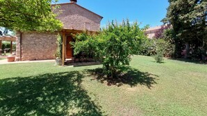 A house with a stone facade, a wooden porch, and a well-maintained lawn.