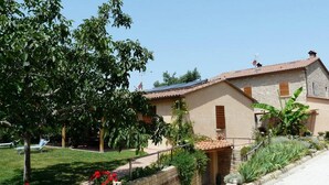 A house with a tiled roof, a garden with a bench, and a small pond.