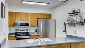 A kitchen with wooden cabinets, stainless steel appliances, and a white countertop. - Lovely 2 BDR Condo - Close to Skiing & Main St! (Breckenridge)