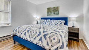 A bedroom with a bed, two bedside tables, a window, and a painting on the wall. - Lovely 2 BDR Condo - Close to Skiing & Main St! (Breckenridge)