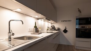 Una cocina moderna con un lavamanos de acero inoxidable, un horno Bosch y una máquina de café espresso montada en la pared.