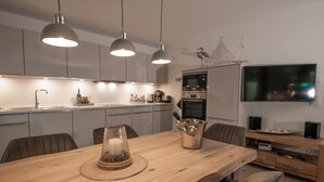 Una cocina moderna con iluminación colgante, una mesa de comedor con un centro de velas y un horno empotrado.