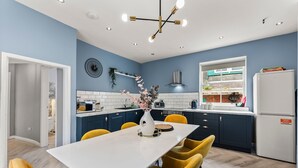 Eine moderne Küche mit einem weißen Tisch, gelben Stühlen und einer blauen Wand.