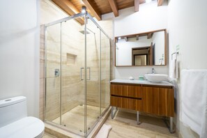 A modern bathroom with a glass shower enclosure, wooden vanity, and a large mirror.