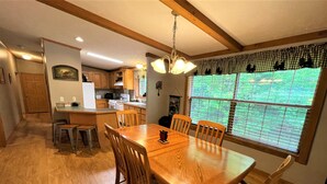 A spacious kitchen with wooden cabinets, a central island, and a dining area with a wooden table and chairs.