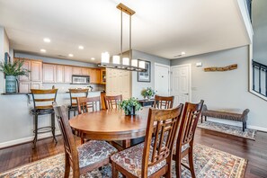 A spacious dining area with a round wooden table and matching chairs, a built-in oven, and a hanging light fixture.