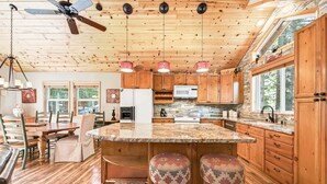 A spacious kitchen with wooden cabinets, a granite countertop, and a ceiling fan. - Bear's Lair by Tahoe Getaways - Luxury Cabin w Hot Tub & HOA Access (Truckee)
