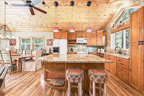 A spacious kitchen with wooden cabinets, a granite countertop, and a ceiling fan.