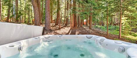 A hot tub surrounded by tall trees in a forested area.