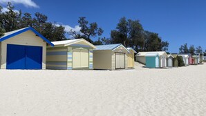 Una serie di casette sulla spiaggia, con una spiaggia sabbiosa e alberi sullo sfondo.