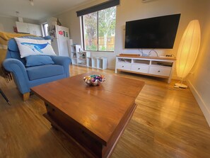 A living room with a blue sofa, a wooden coffee table, a TV, and a lamp.