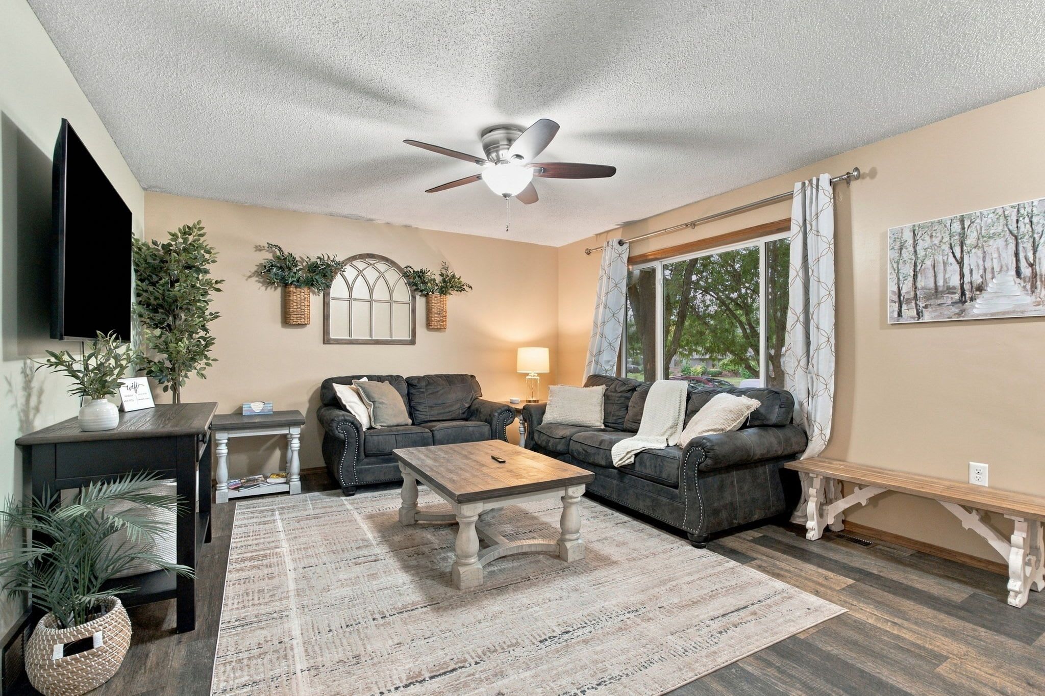 A living room with a ceiling fan, two couches, a coffee table, a TV, and a painting on the wall.