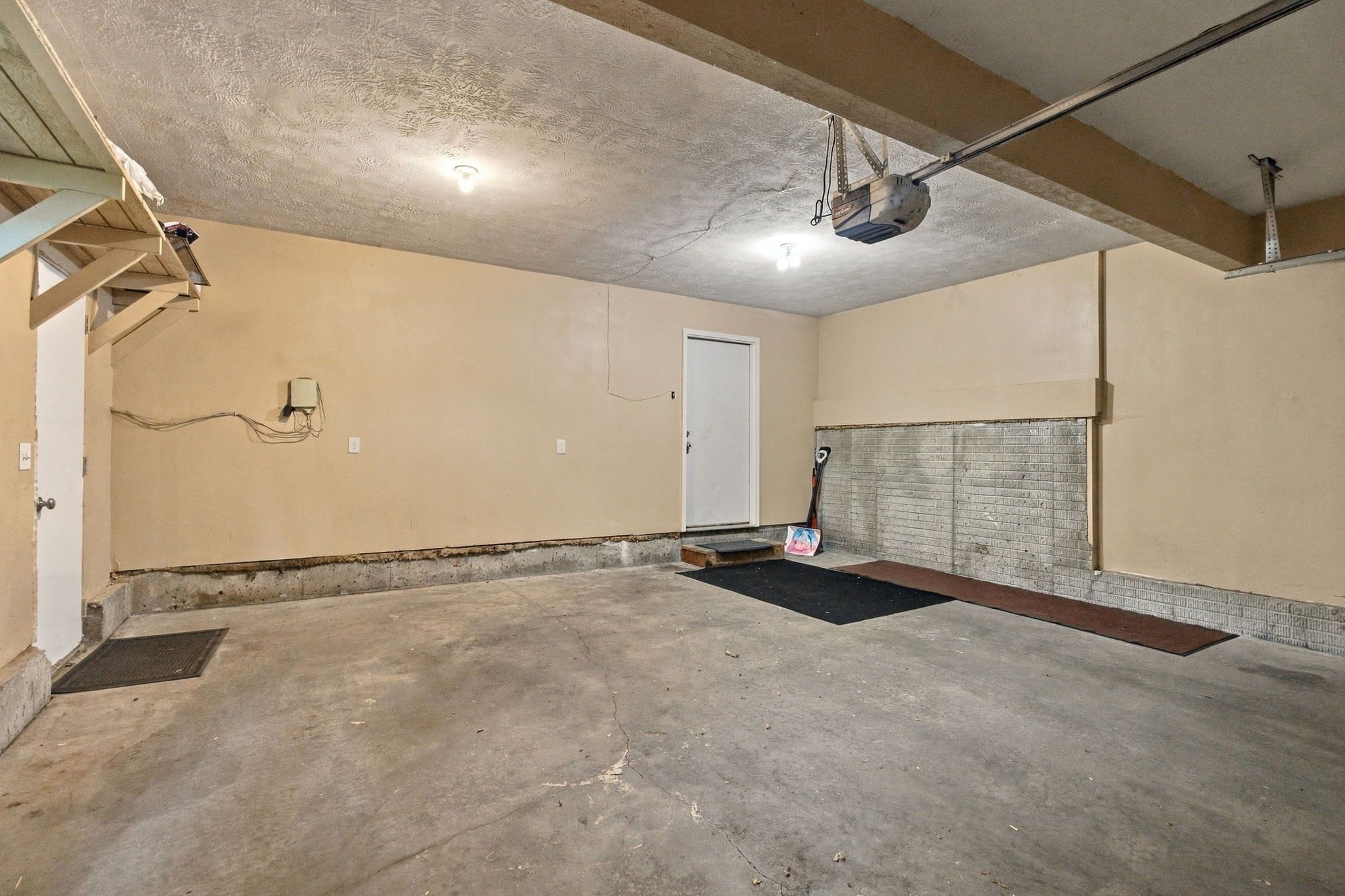 Un sous-sol avec un plancher en béton, une porte et une structure en poutres métalliques.