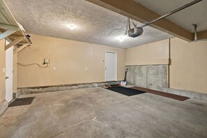 Ein Kellerraum mit Betonboden, einer Tür und einer Stahlträgerkonstruktion.