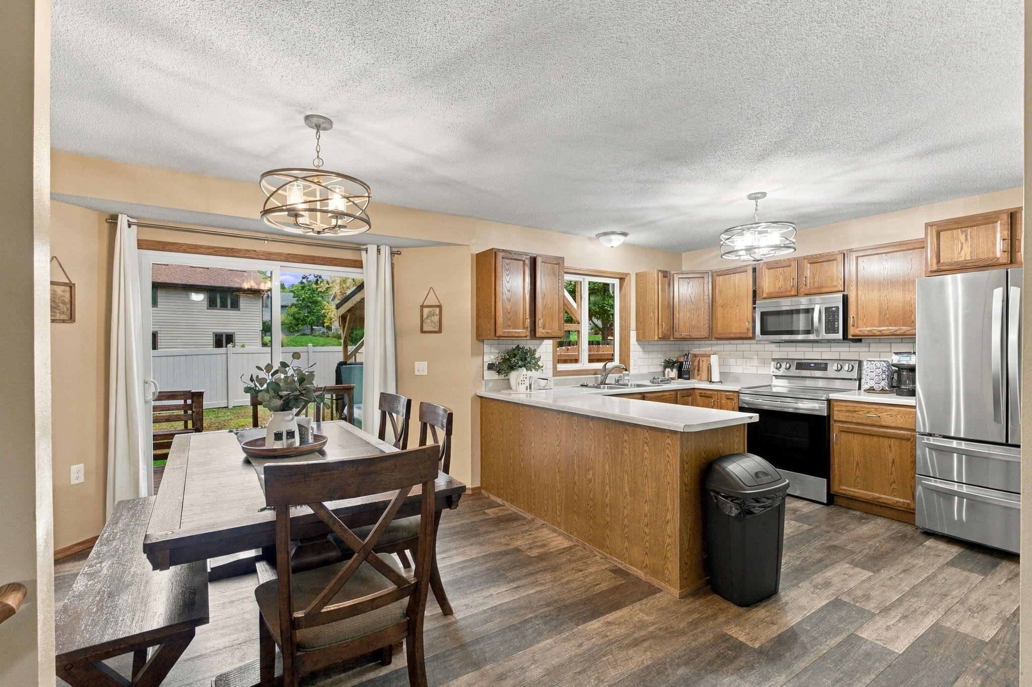 A modern kitchen with wooden cabinets, stainless steel appliances, and a dining area with a bench and chairs.