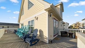Une terrasse en bois avec plusieurs chaises Adirondack et une petite table.