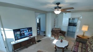 A living room with a television, a ceiling fan, a coffee table, and a sofa. - Rancher's Capitol Lodge (Historic) - Steps away from the Capitol and Downtown (Cheyenne)