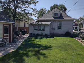 A residential house with a well-maintained lawn, a small patio area, and a garage.