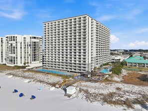 A high-rise hotel with multiple balconies, a pool area, and a beach access point.
