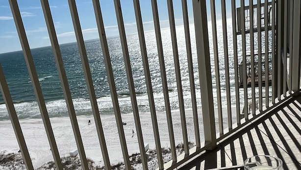 A beach view from a balcony with a tray of donuts and milk.