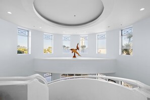 Ein modernes Interieur mit einer zentralen weißen Plattform, einer Skulptur und einem Zitat aus 'Die Brücken von Madison County' von Robert James Waller.