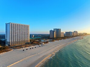 A coastal cityscape with high-rise buildings, a sandy beach, and a clear sky.