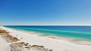 A beach with a clear blue sky, a sandy shore, and a calm sea.