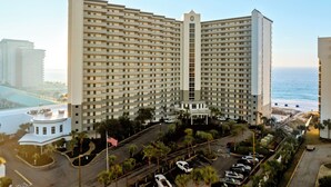 A high-rise hotel with a central atrium, multiple floors, and a view of the ocean.
