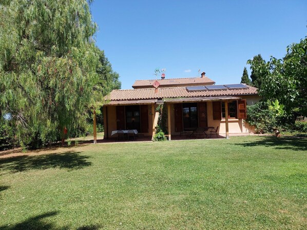 A house with a tiled roof, a covered porch, and a lawn.
