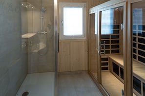 Ein modernes Badezimmer mit Duschkabine aus Glas, einem Holzwaschtisch und einem Fenster für natürliches Licht.