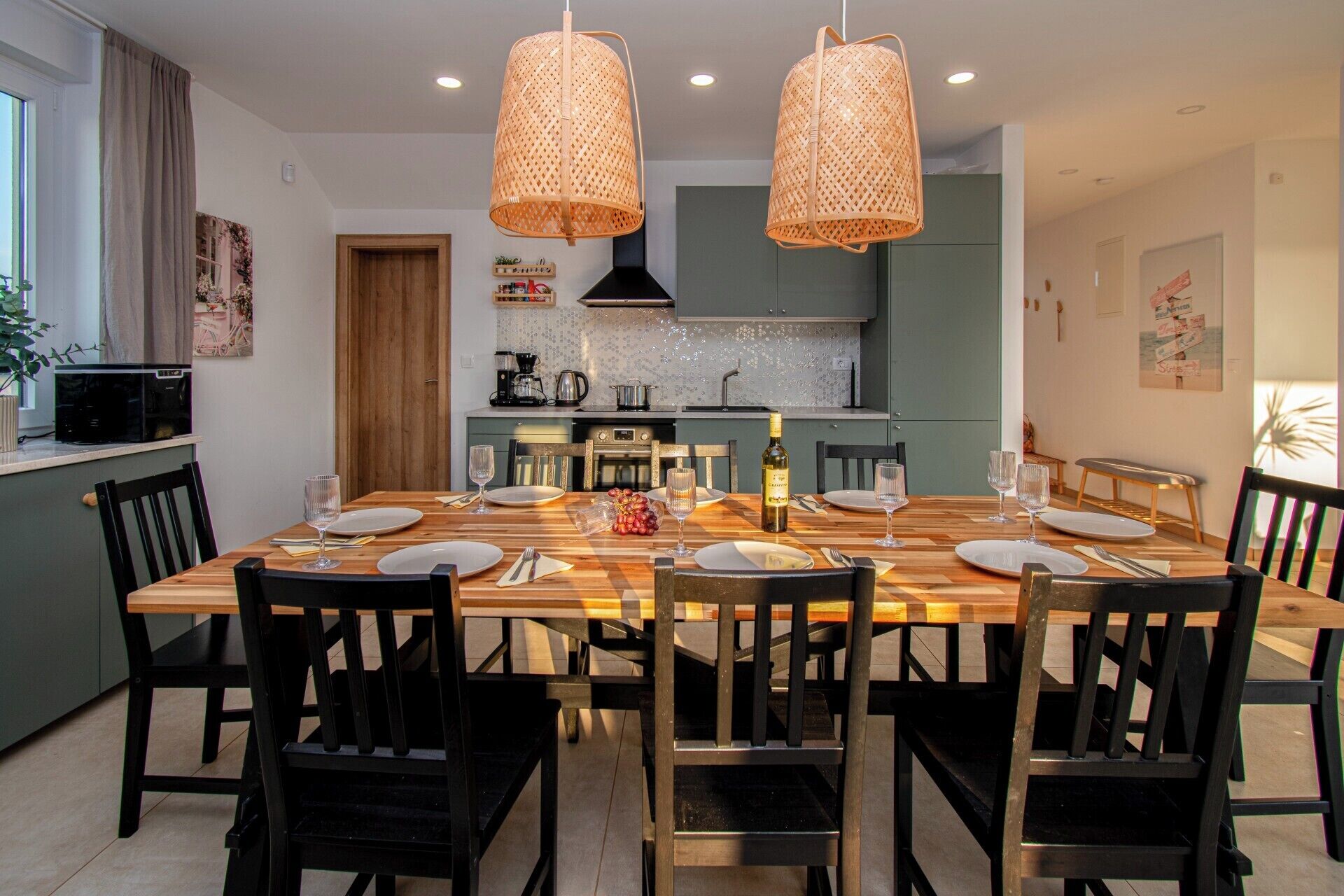 Comedor con mesa de madera para seis, sillas negras y dos lámparas de mimbre colgantes.