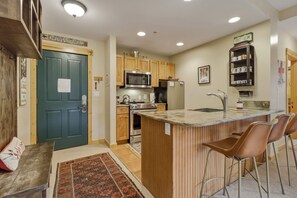 A kitchen with wooden cabinets, a built-in microwave, a stainless steel refrigerator, and a marble countertop. - Spacious, Mountain Chic, Close to Ski Lift 1 bedroom (Copper Mountain)