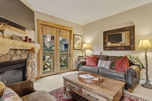 A cozy living room with a fireplace, a sofa, a coffee table, and a television. - Spacious, Mountain Chic, Close to Ski Lift 1 bedroom (Copper Mountain)
