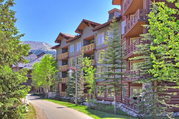 A multi-story hotel with balconies, a paved driveway, and surrounding greenery.