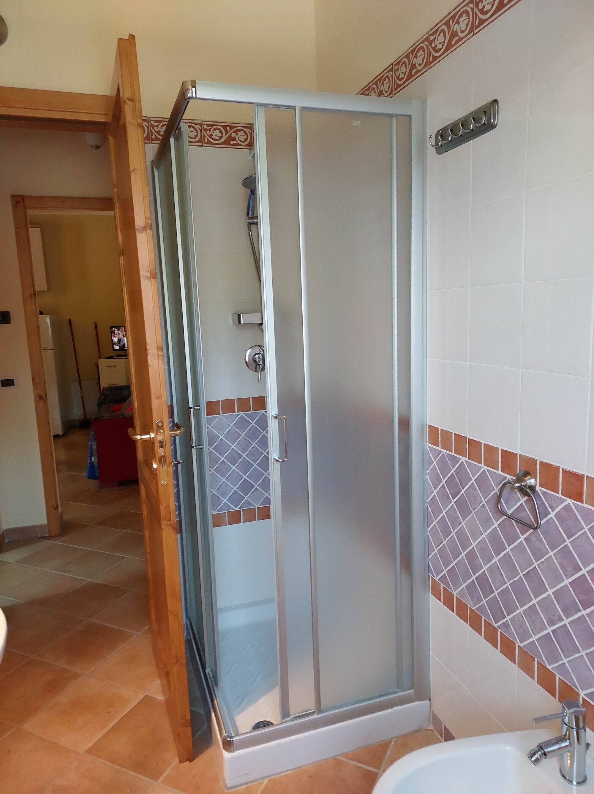 A shower enclosure with a glass door, a tiled shower area, and a sink with a faucet.