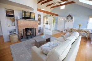 Ein Wohnzimmer mit Kamin, weißen Sofas, einem Couchtisch und einem an der Wand montierten Fernseher.