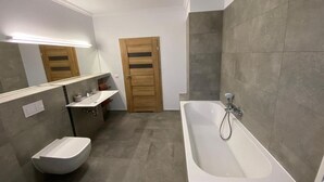 Un baño moderno con una bañera independiente, un bidé y un tocador con espejo.