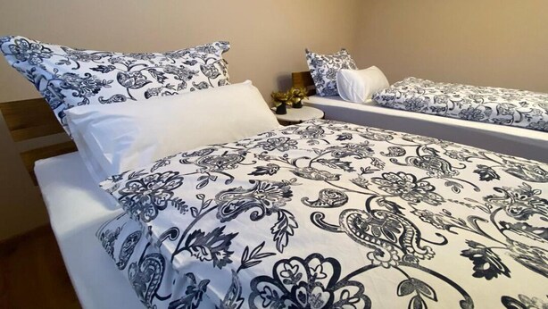 Habitación de hotel con dos camas, cada una con ropa de cama y almohadas estampadas.